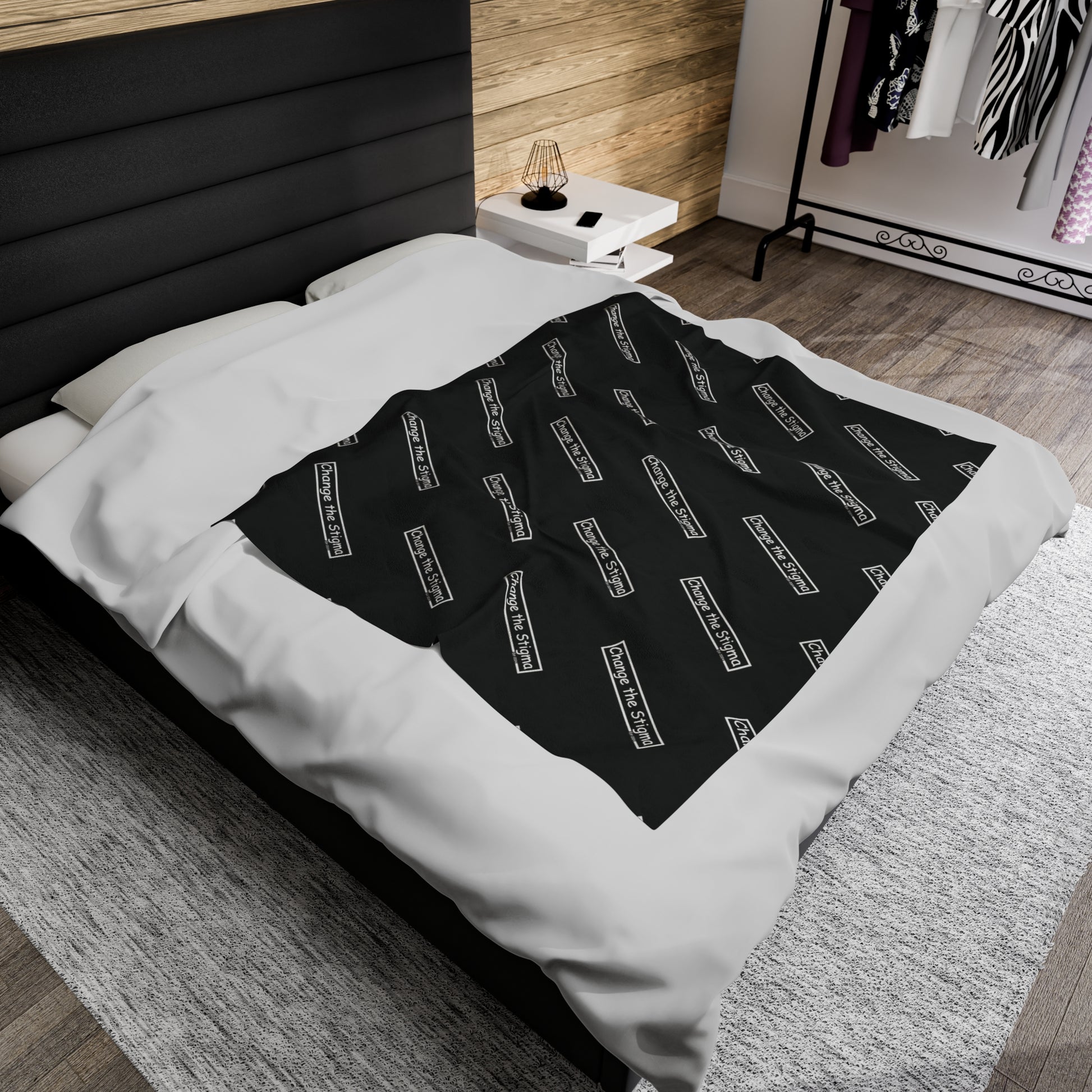 Blanket shown on a large bed. BLACK FLEECE BLANKET 50"x60". This is showing the top of the image. the words "Change the Stigma" across is on a pattern.